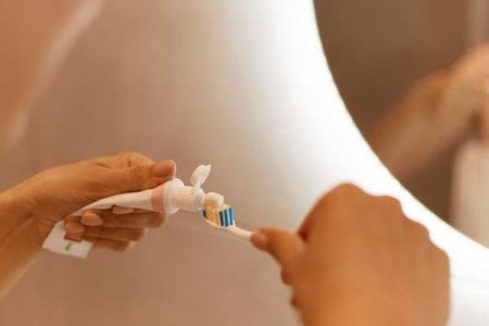 compressed-close-up-portrait-woman-hands-front-mirror-bathroom-holding-toothpaste-toothbrush-...jpeg