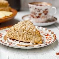 Side view of maple glazed Apple Cinnamon Scone on a brown and white plate