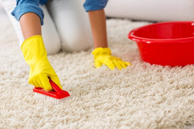 Woman washing carpet with brush