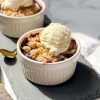 Side view of Individual Berry Crisps in a white ramekin on a black slate board.