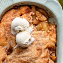 apple cobbler with cinnamon sugar and ice cream on top.