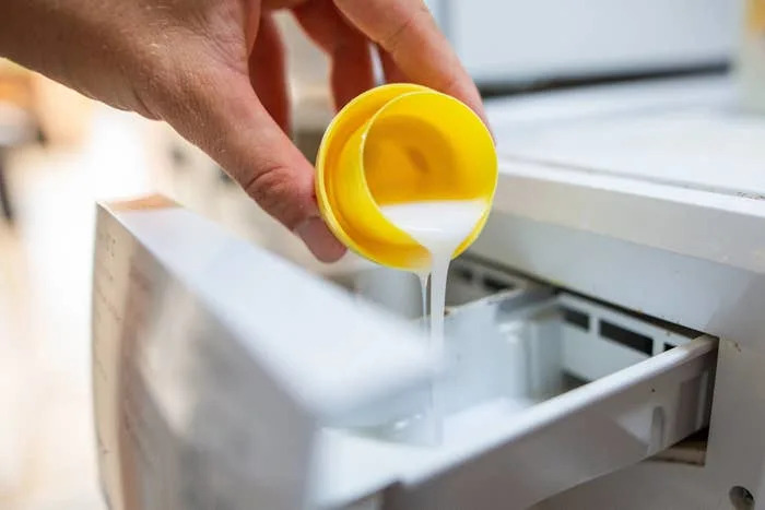 Pouring liquid detergent into washing machine dispenser