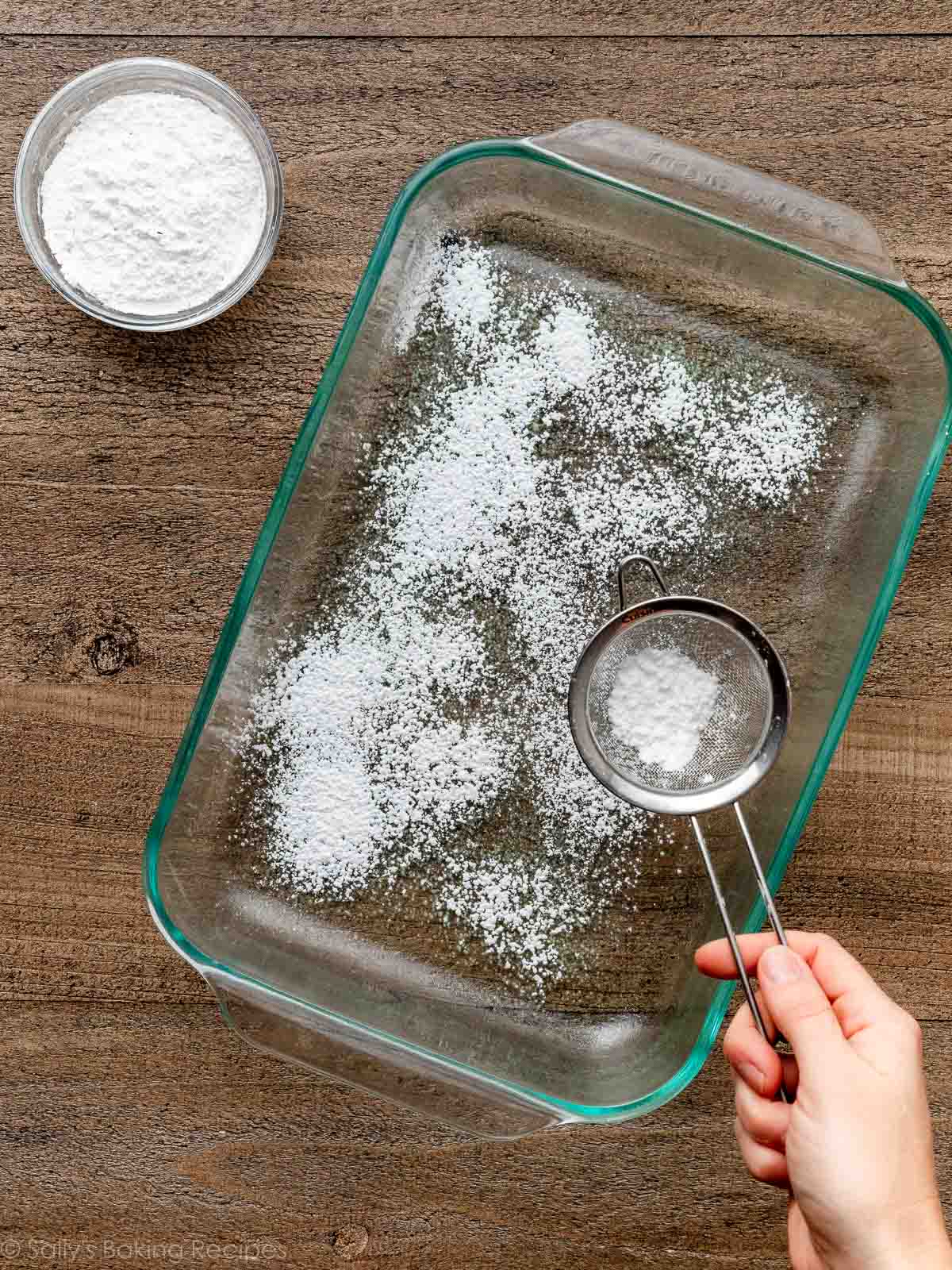 sifting confectioners' sugar and cornstarch in a glass pan. sifting confectioners' sugar and cornstarch in a glass pan.