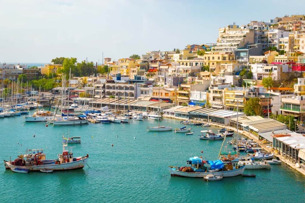 Image of boats in water in the Island of Crete with homes overlooking the water